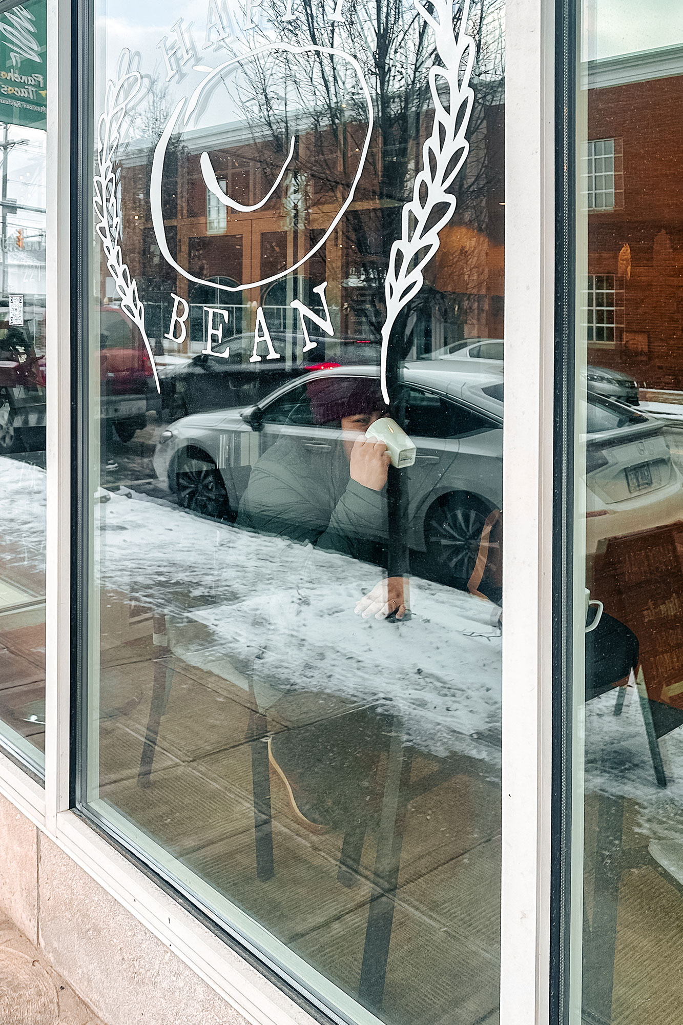 A woman sipping hot cocoa through a cozy coffee shop window, enjoying a moment of relaxation.
