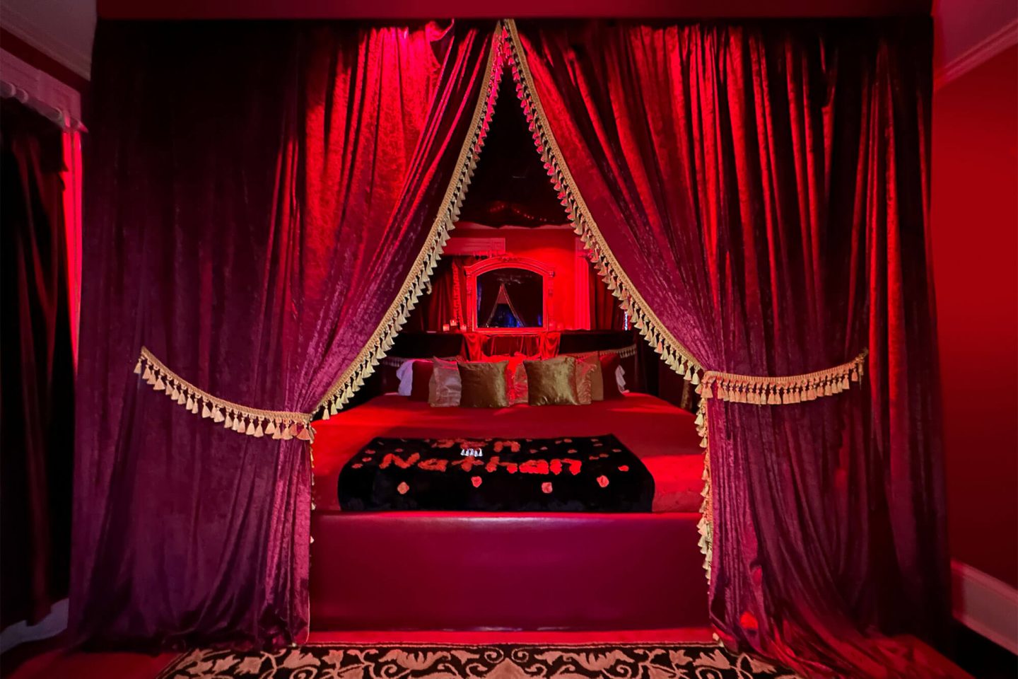 A massive bed with draped curtains and rose petals arranged with our names, creating a romantic and memorable atmosphere during a stay at Romantic Adventure Getaways