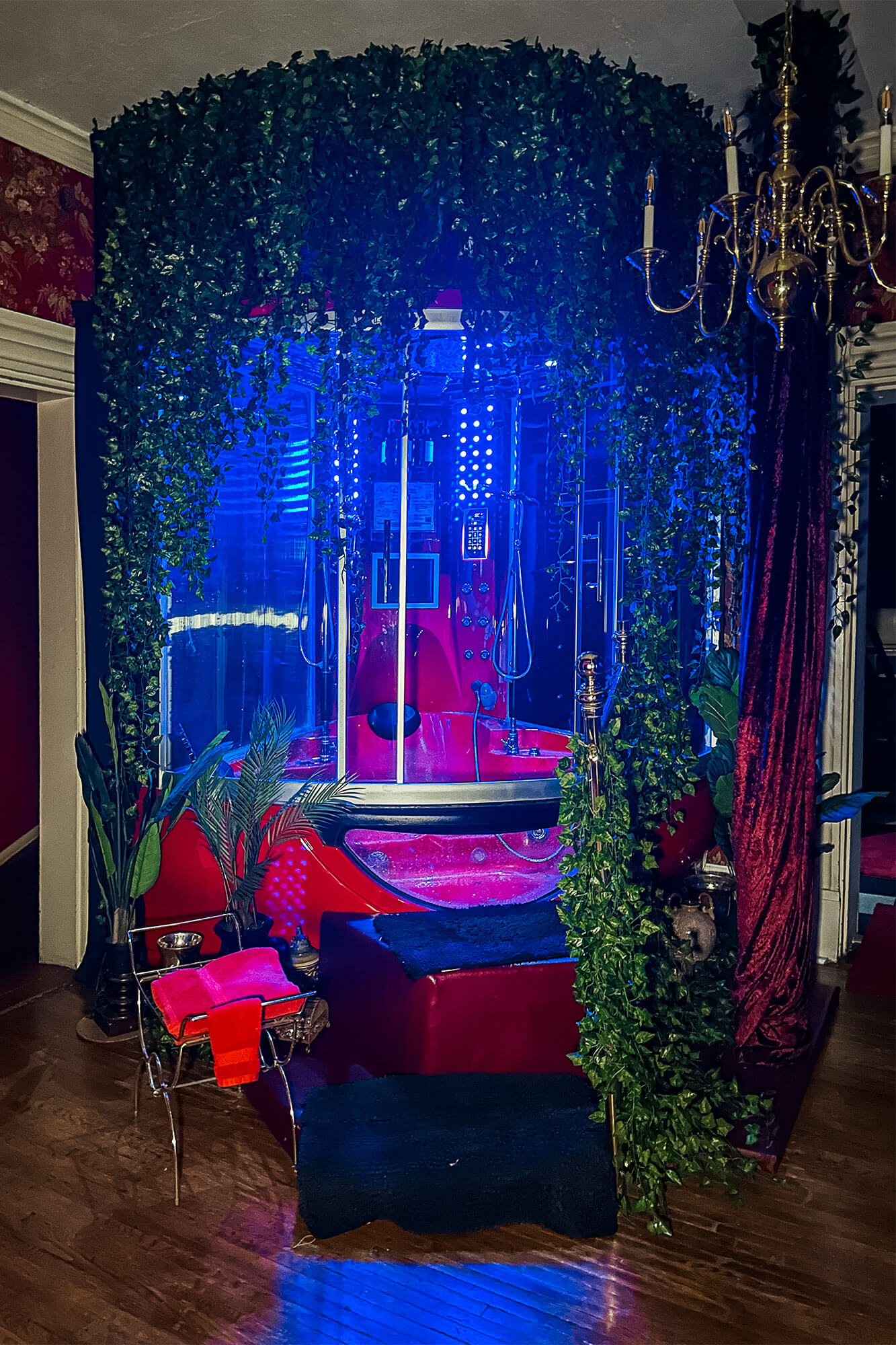 Dimly lit Mayan Rainforest Jet Tub with red walls and glowing blue light, creating a tropical feel.